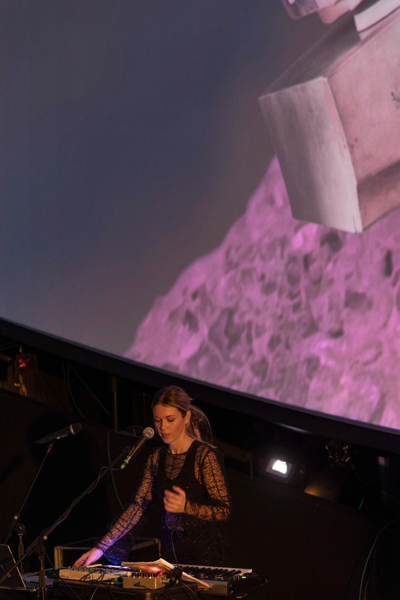 Loljud performing at a keyboard below the dome screen at Wisdome Malmö, with pink projections above
